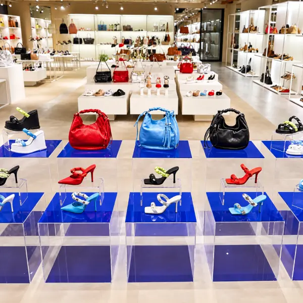 Pedestais em acrílico azul expondo sapatos e bolsas na loja Arezzo